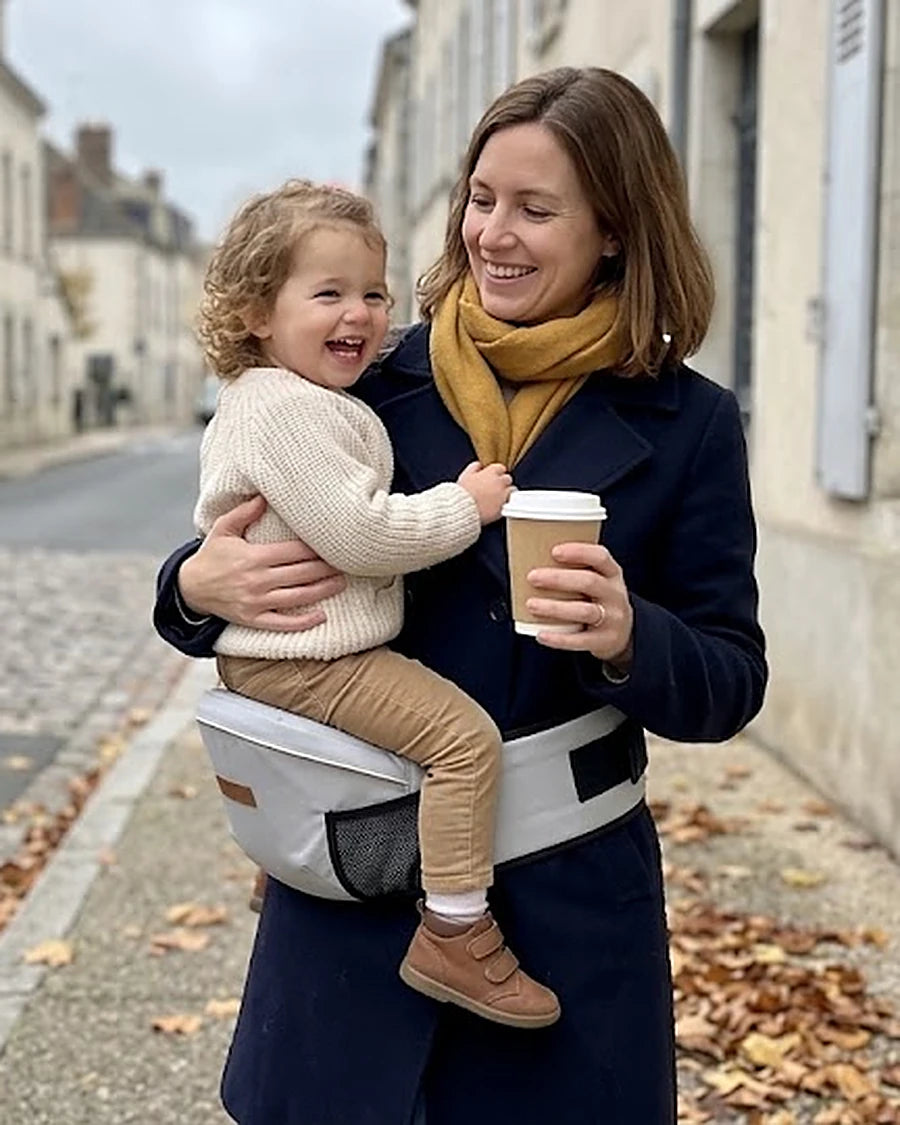 Maman et son enfant front contre front, l’enfant assis sur le porte-bébé à hanche
